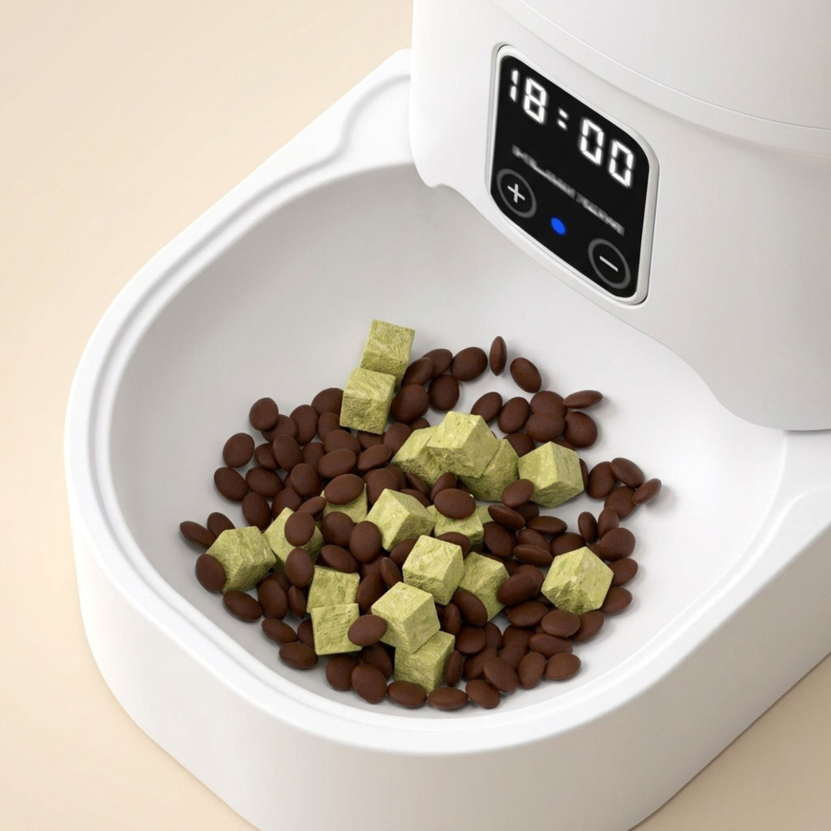 gros plan sur le bol blanc du distributeur automatique de croquettes pour chat rempli de croquettes rondes marron et morceaux verts avec écran LCD affichant 18:00