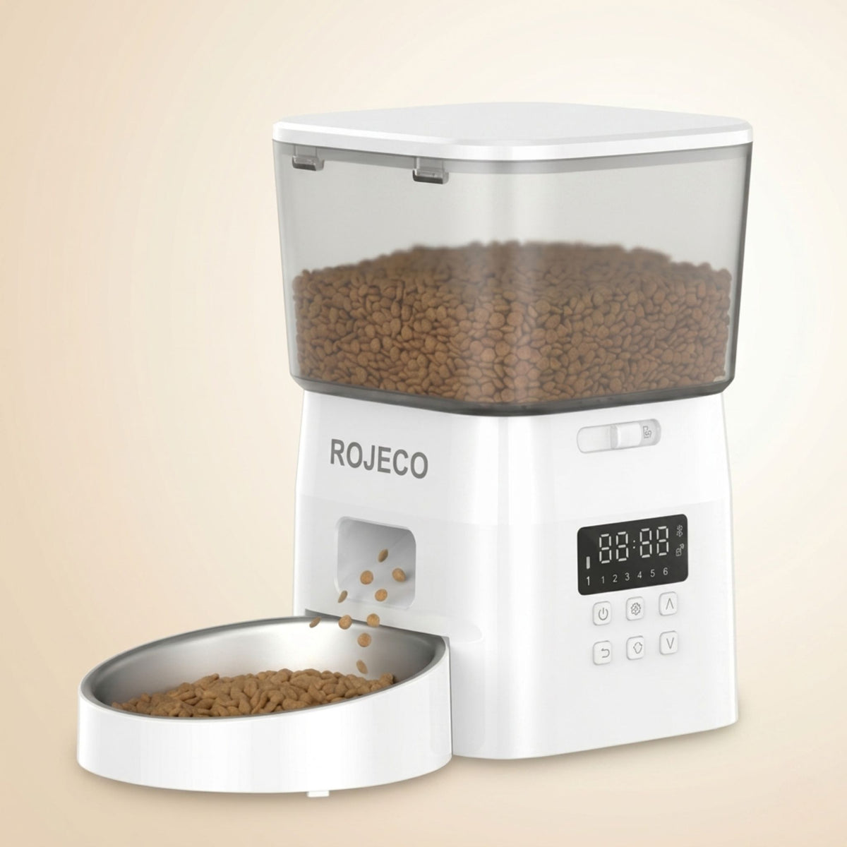 distributeur automatique croquettes pour chat blanc avec réservoir transparent plein de croquettes, bol inox et croquettes qui tombent, fond beige crème