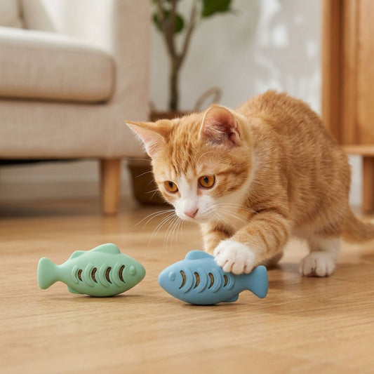 Chaton roux jouant avec deux jouets poisson distributeurs de croquettes en silicone – coloris vert mint et bleu – sur parquet clair, ambiance intérieur cosy