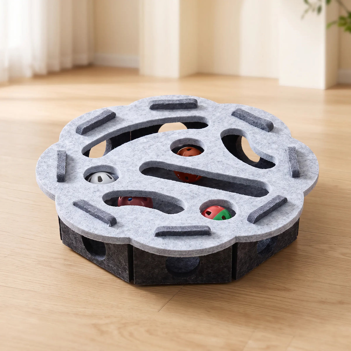 Jouet puzzle pour chat au plateau festonné gris clair sur caisson anthracite, balles visibles par les découpes